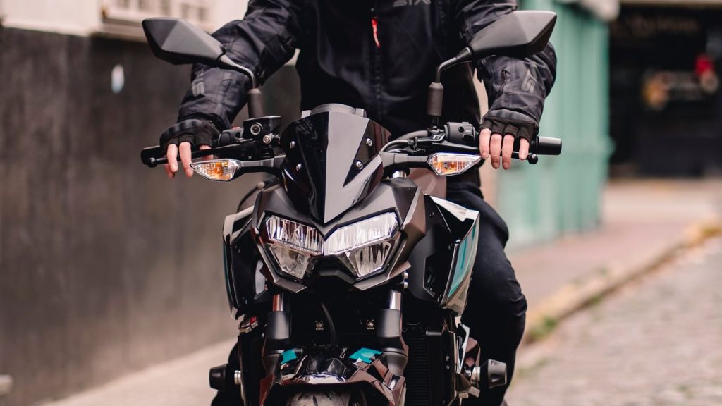 Front view of a motorcyclist riding on city streets, emphasizing modern design and gear.